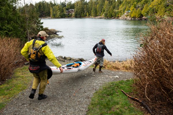 Two people carry a fully loaded kayak toward the ocean in order to launch. 